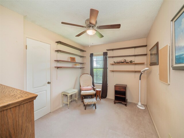 sitting room with carpet flooring, a textured ceiling, and ceiling fan