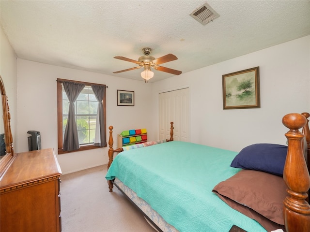 bedroom with carpet floors, a textured ceiling, ceiling fan, and a closet