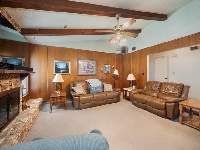 living room featuring a stone fireplace, ceiling fan, carpet, and wooden walls