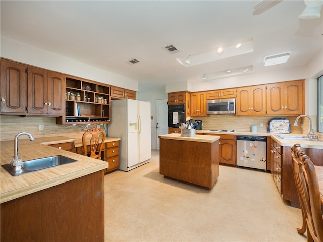 kitchen with sink, decorative backsplash, a kitchen island, and stainless steel appliances