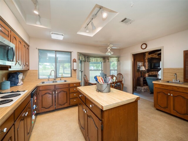 kitchen featuring butcher block countertops, sink, light carpet, and ceiling fan