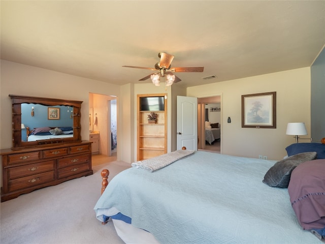 bedroom featuring light colored carpet, ensuite bathroom, and ceiling fan