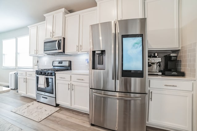 kitchen featuring appliances with stainless steel finishes, light hardwood / wood-style flooring, backsplash, and white cabinetry