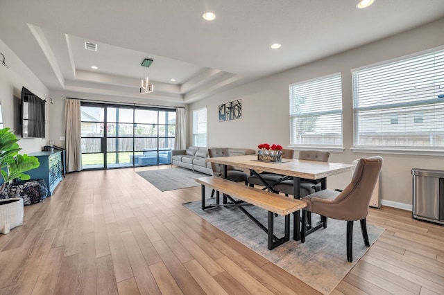 dining area with light hardwood / wood-style flooring and a raised ceiling