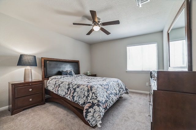 bedroom featuring light colored carpet, a textured ceiling, and ceiling fan