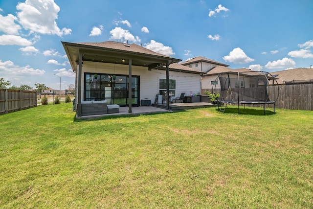 rear view of property with a patio, a trampoline, and a yard