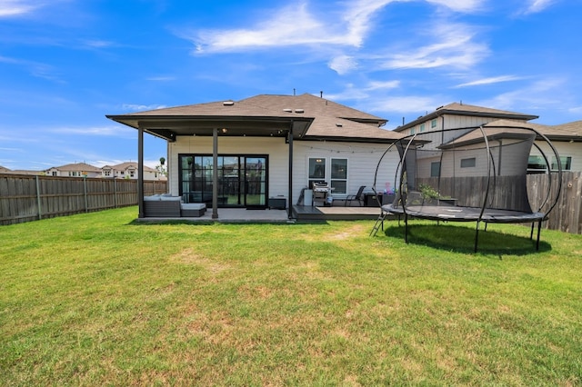 rear view of property with a patio, a trampoline, and a yard