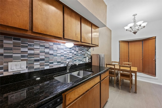 kitchen featuring light tile patterned flooring, dark stone countertops, a notable chandelier, decorative backsplash, and sink