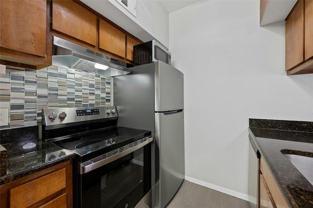 kitchen featuring dark stone counters, stainless steel electric range oven, decorative backsplash, and tile patterned flooring