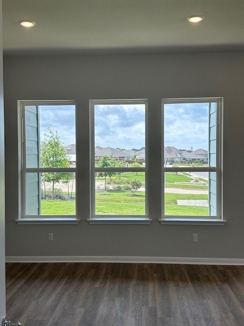 empty room with a wealth of natural light and dark hardwood / wood-style floors