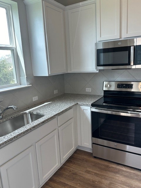 kitchen with tasteful backsplash, stainless steel appliances, dark hardwood / wood-style flooring, white cabinets, and light stone counters