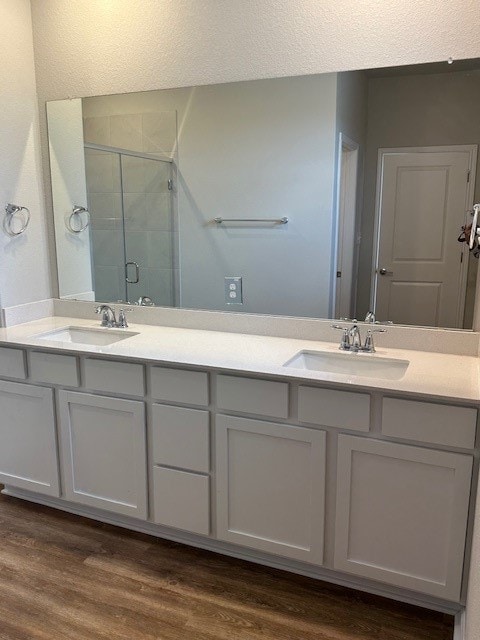 bathroom with an enclosed shower, hardwood / wood-style flooring, and dual bowl vanity