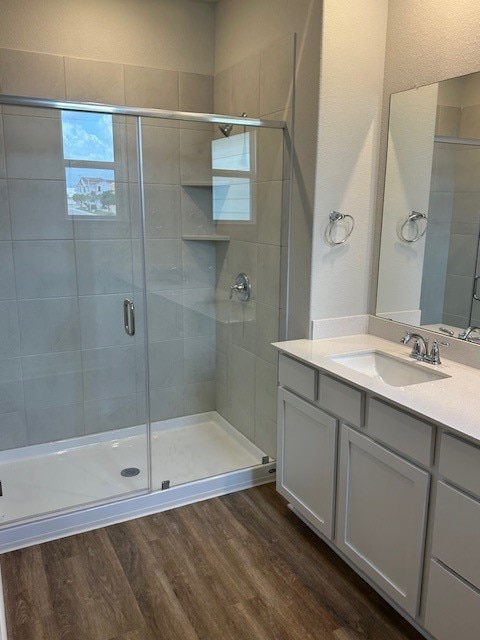 bathroom with hardwood / wood-style flooring, vanity, and an enclosed shower