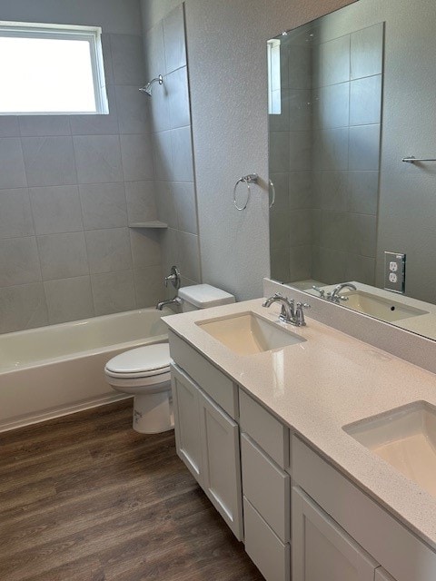 full bathroom with tiled shower / bath combo, toilet, hardwood / wood-style flooring, and double sink vanity