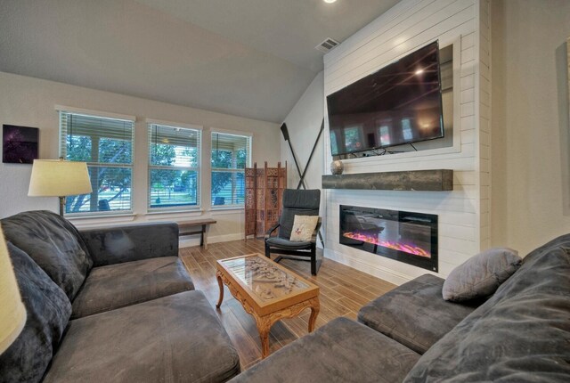 living room featuring a large fireplace and vaulted ceiling