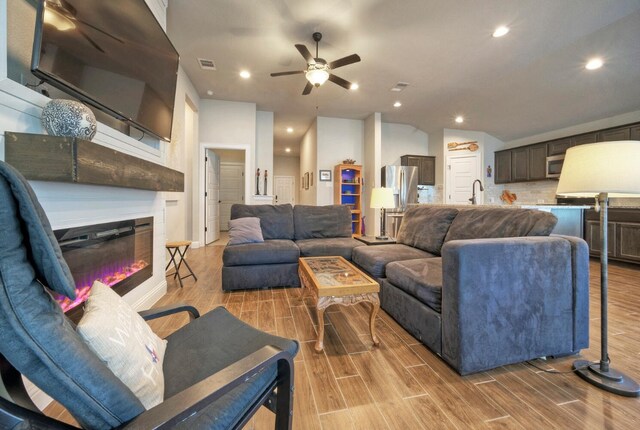 21707 Crystal Way, Lago Vista, TX 78645 - living room featuring a ceiling fan, light wood-style floors, a glass covered fireplace, recessed lighting, and lofted ceiling