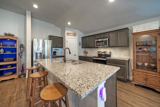 21707 Crystal Way, Lago Vista, TX 78645 - kitchen featuring appliances with stainless steel finishes, a sink, wood finish floors, backsplash, and vaulted ceiling