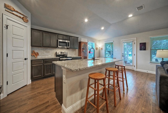 kitchen featuring a center island with sink, a kitchen breakfast bar, sink, vaulted ceiling, and stainless steel appliances