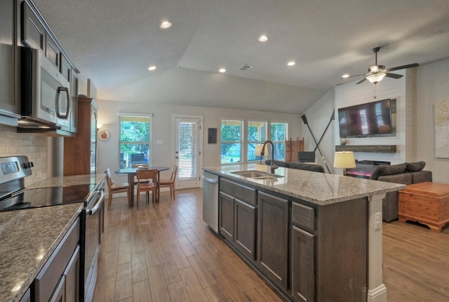 kitchen with sink, lofted ceiling, stainless steel appliances, and an island with sink