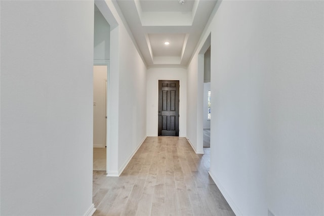 corridor featuring light hardwood / wood-style floors and a raised ceiling