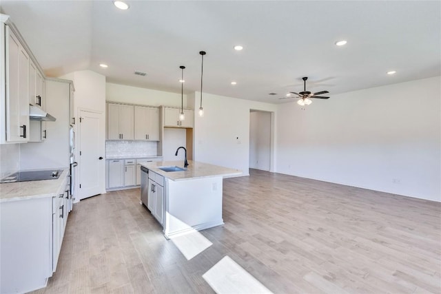 607 Breeze Hollow Ln, Georgetown, TX 78628 - kitchen with under cabinet range hood, a ceiling fan, black electric stovetop, light wood-style floors, and a center island with sink