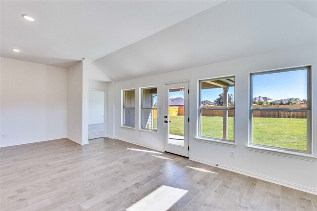 unfurnished room featuring lofted ceiling and light hardwood / wood-style flooring