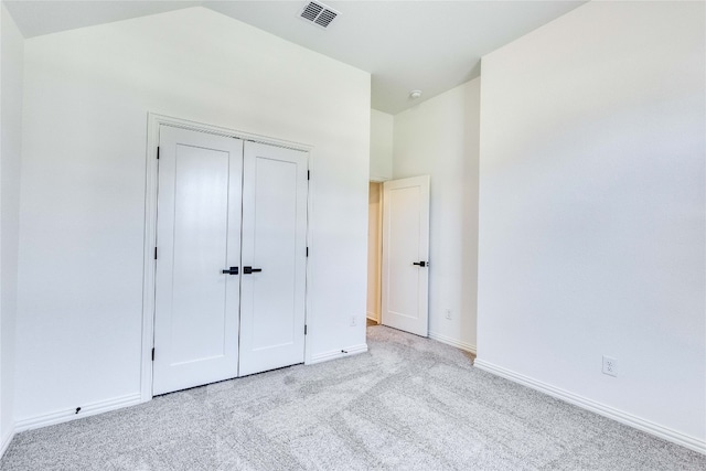 unfurnished bedroom featuring light colored carpet and a closet