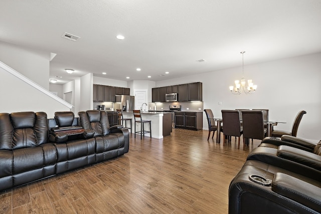 living room with an inviting chandelier, sink, and hardwood / wood-style floors