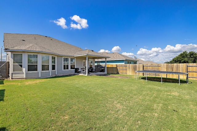 rear view of house featuring a trampoline, a patio, and a yard