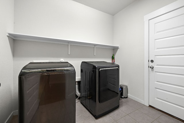 clothes washing area featuring light tile patterned floors and washing machine and clothes dryer