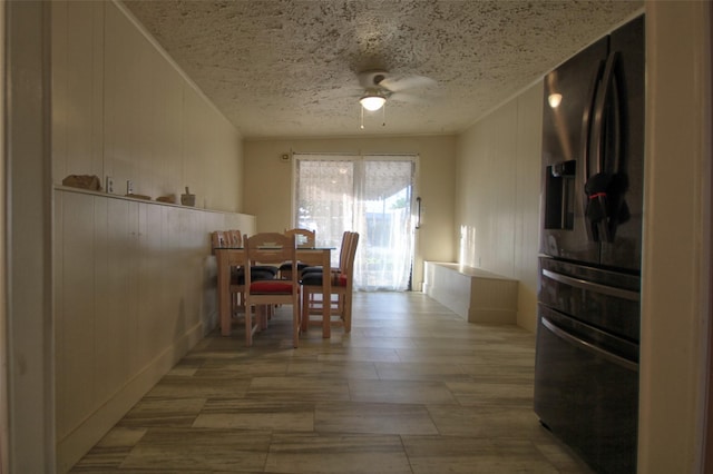 dining area featuring ceiling fan and wood walls