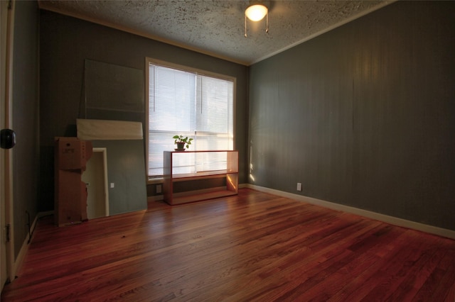 unfurnished room with ornamental molding, a textured ceiling, and dark hardwood / wood-style flooring