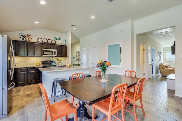 dining room with light hardwood / wood-style flooring, sink, and vaulted ceiling