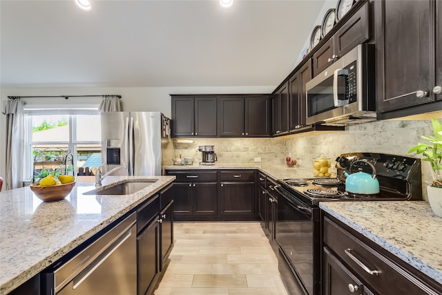 kitchen with light stone counters, stainless steel appliances, dark brown cabinets, and sink