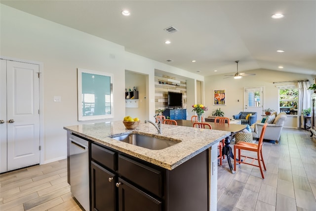 kitchen featuring lofted ceiling, an island with sink, stainless steel dishwasher, light hardwood / wood-style flooring, and sink