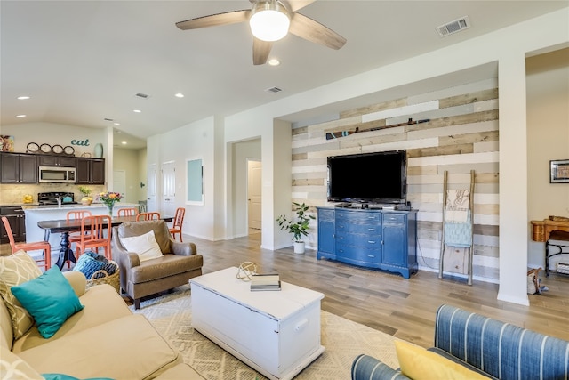 living room featuring vaulted ceiling, light hardwood / wood-style flooring, and ceiling fan