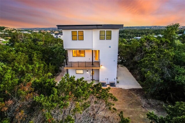 back house at dusk featuring a balcony and central AC unit