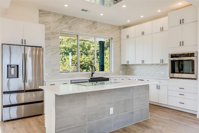 kitchen with sink, a kitchen island, white cabinets, and appliances with stainless steel finishes