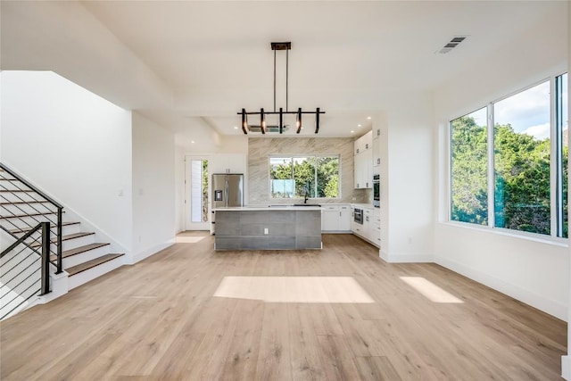 15000 Texas St, Austin, TX 78734 - unfurnished living room featuring a sink, light wood-style floors, baseboards, stairs, and recessed lighting