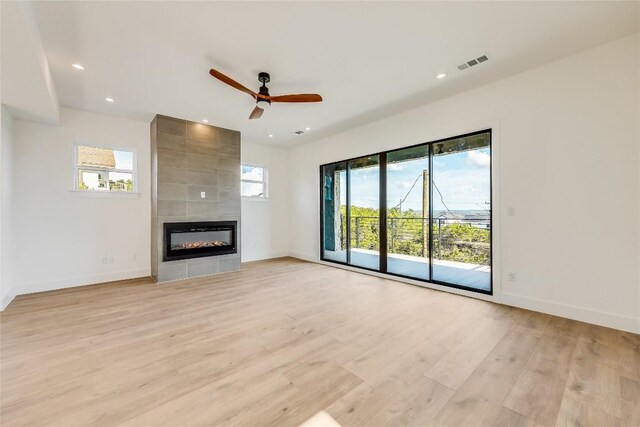 unfurnished living room with plenty of natural light, a fireplace, ceiling fan, and light hardwood / wood-style floors