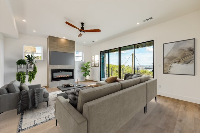 living room with wood-type flooring, a tile fireplace, and ceiling fan