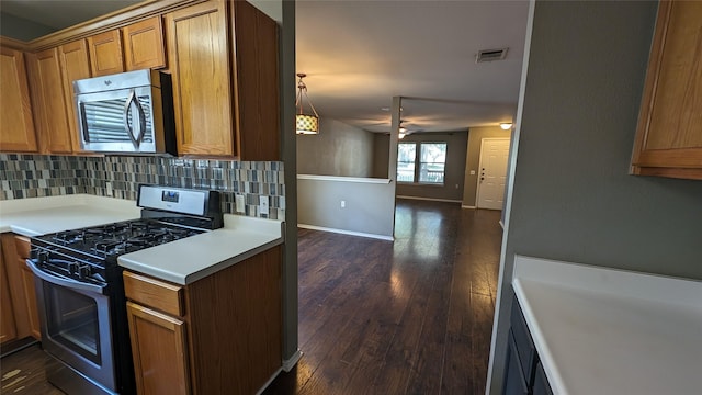 kitchen featuring ceiling fan, dark hardwood / wood-style flooring, appliances with stainless steel finishes, and tasteful backsplash