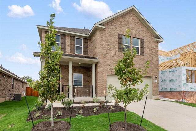 view of front of home with a garage, a front lawn, and central AC unit