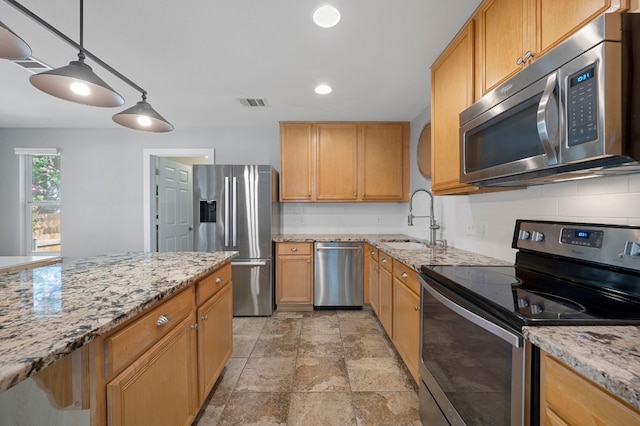 kitchen with backsplash, sink, hanging light fixtures, appliances with stainless steel finishes, and light stone counters