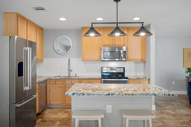 kitchen with stainless steel appliances, tasteful backsplash, sink, hanging light fixtures, and a breakfast bar area