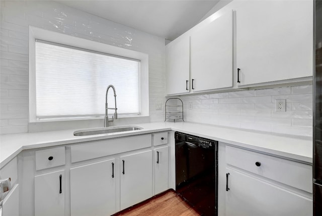 kitchen with white cabinetry, black dishwasher, sink, and tasteful backsplash