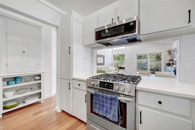 kitchen featuring white cabinetry, decorative backsplash, light hardwood / wood-style floors, and appliances with stainless steel finishes