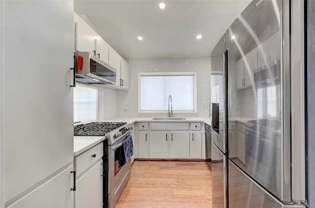 kitchen featuring white cabinetry, appliances with stainless steel finishes, sink, and light wood-type flooring