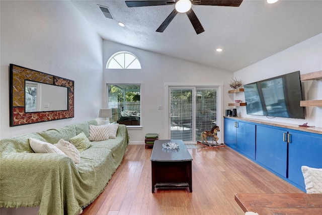 living room with hardwood / wood-style floors, vaulted ceiling, a textured ceiling, and ceiling fan