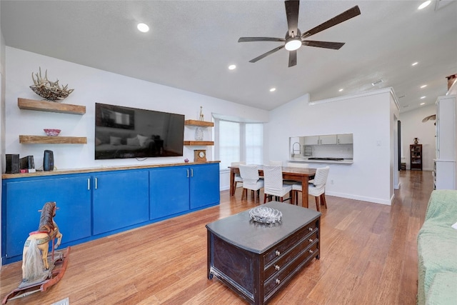 living room featuring sink, vaulted ceiling, ceiling fan, and light wood-type flooring